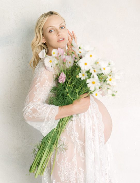 Pregnant mother holding flowers in a natural light maternity portrait